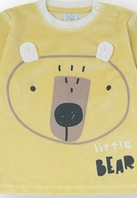 Camiseta amarilla de manga larga con diseño de cara de oso con orejas, forma redondeada y textura suave. Texto "Little Bear" en negro negrita.