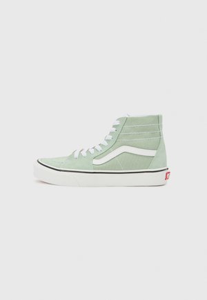 Baskets montantes en suède vert avec des lacets blancs, présentant une bande latérale blanche, un contour noir et une étiquette logo rouge sur le talon.