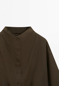 Braunes Hemd mit Knopfleiste, hohem Kragen und langen Ärmeln, aus strukturiertem Stoff, vor einfarbigem Hintergrund dargestellt.