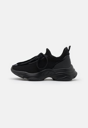 Baskets de sport entièrement noires avec une tige en maille texturée, une semelle épaisse, une languette au talon et des lacets ronds sur un fond clair uni.