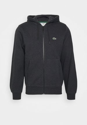 Sweat à capuche zippé intégral gris foncé avec capuche à cordon, poches avant, poignets côtelés et petit logo crocodile vert sur la poitrine gauche.