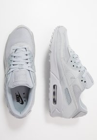 Gaišpelēku Nike Air Max sporta apavi ar sietu un sintētisko ādu, apaļa purngala forma, redzama gaisa padeve un teksturēta zole.