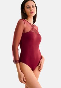 Bodysuit bourgogne avec des manches longues en mesh transparent et des détails en dentelle au niveau du col. Design ajusté avec une texture lisse et une délicate bordure en dentelle.