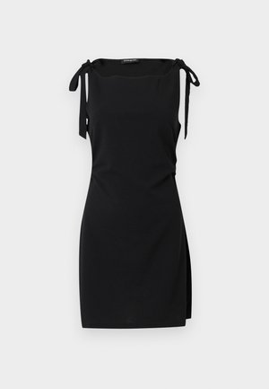 Abito mini nero senza maniche con spalline annodate e uno spacco su un lato, esposto su uno sfondo chiaro uniforme.