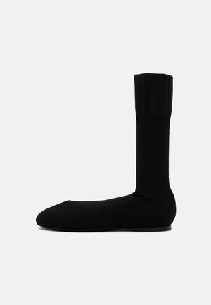Schwarze gestrickte Knöchelsocken, gerippte Design, geschlossene Zehenform, glatte Textur, mit einer flachen Gummisohle für besseren Halt.