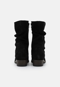 Bottines en daim noir avec un design flou, dotées d'un petit talon empilé et de zips sur les côtés pour un enfilage facile.