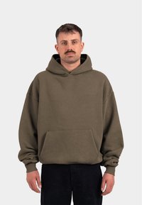 Olivgrüner Hoodie mit einer Kängurutasche, oversized Schnitt und Kordelzug. Hergestellt aus weichem Stoff, mit gerippten Bündchen und Saum.