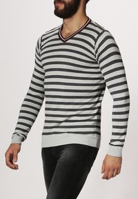 Randig grå och vit tröja med V-ringning, ribbade muddar och fåll, med horisontella streck i växlande bredder. Slim fit-design.