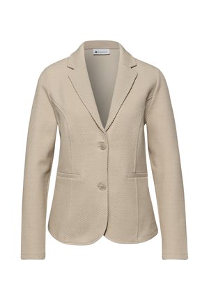 Blazer beige texturé pour femme avec deux boutons, revers crantés, et deux poches avant, présenté sur un fond blanc.