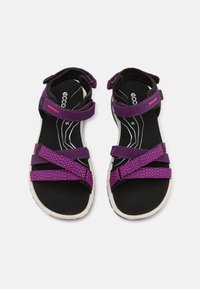 Fialové sandály s vzorovanými pásky, nastavitelné suché zipy a černou polstrovanou stélkou. Bílá gumová podrážka s texturovaným gripem.