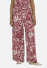 Pantaloni a gamba larga realizzati in tessuto leggero, caratterizzati da un motivo floreale rosso e bianco. Il design include foglie e fiori dettagliati.