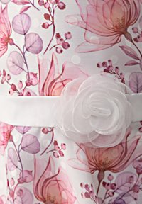 Valkoinen kukkamekko, jossa on vaaleanpunaisia ja violetteja kukkakuvioita, teksturoitu kangas ja valkoinen satiinivyö, jossa on kerroksellinen kangaskukkakoriste.