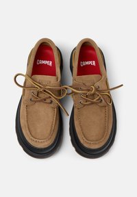Tan suede shoes with black rubber soles. Rounded toe design, featuring yellow laces and red insoles with "CAMPER" branding.
