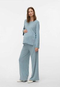 Set di abbigliamento da casa per maternità in azzurro chiaro, composto da una maglia a maniche lunghe con un nodo laterale e pantaloni a gamba larga, realizzato in un morbido tessuto texturizzato.