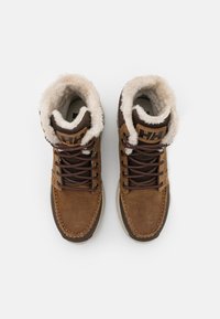 Bottes cheville en cuir brun avec une doublure en fausse fourrure, présentant des lacets ronds, un col rembourré et une semelle en caoutchouc texturée. Logo sur la languette.