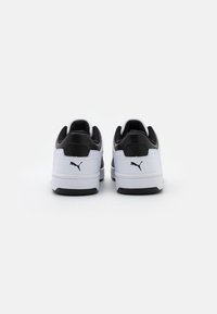 Baskets noires et blanches avec une tige en cuir texturé, un col rembourré et une semelle en caoutchouc noire. Présentent un petit logo de la marque sur le talon.