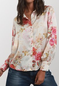 Blusa floreale in seta crema con motivi rosa e rossi, con chiusura a bottoni frontale, maniche lunghe e vestibilità rilassata. Tessuto testurizzato.