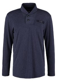 Mörkblå skjorta med lång ärm, krage, tvåknapplåsning och tygpatch med "RAW"-logotyp på framsidan. Mjuk, texturerad material.