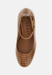 Ballerine plate couleur camel avec une texture en fausse peau de serpent. Elle possède un bout arrondi et un petit détail de boucle sur le côté. Intérieur étiqueté "GUESS".