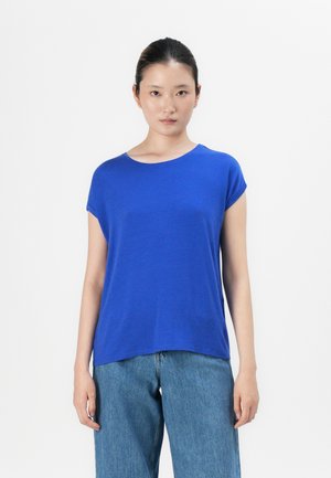 Blå t-skjorte med korte ermer, rund hals og avslappet passform, laget av myk stoff. Kombinert med løstsittende blå jeans.