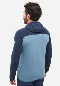 Polarowy hoodie z granatowym kapturem i rękawami oraz jasnoniebieską tylną częścią. Gładka tekstura, bez widocznych wzorów czy elementów metalowych.