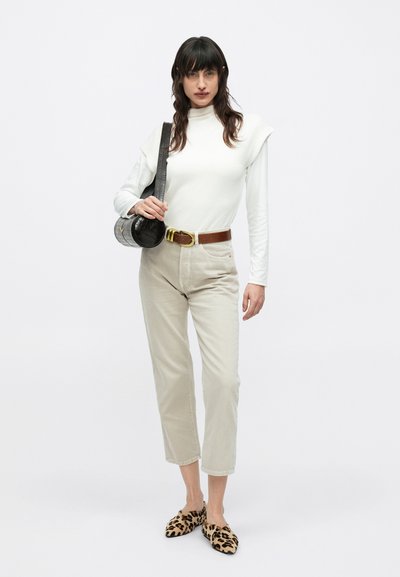 Λευκό πλεκτό ζιβάγκο, μπεζ παντελόνι ψηλόμεσο, καφέ ζώνη, γκρι τσαντάκι ώμου με υφή και παπούτσια τύπου slip-on με λεοπάρ σχέδιο.