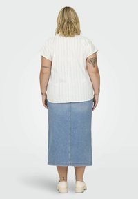 Top blanco a rayas con mangas cortas combinado con una falda maxi de mezclilla azul claro. Diseño simple con un corte holgado y costuras planas. Calzado informal.