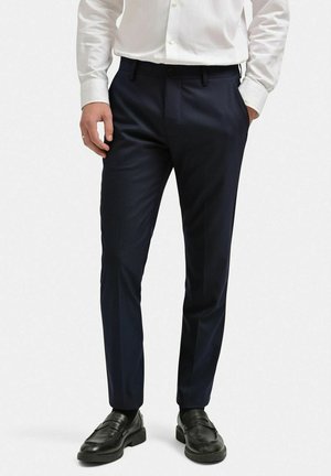 Marina klädpants i en slät tygkvalitet, med skräddarsydd passform, sidofickor och knappstängning. I kombination med svarta loafers.