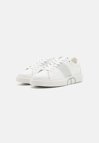 Sneakers bianche con chiusura a lacci, materiale in pelle liscia, accenti in rete sui lati e dettaglio del logo sulla suola esterna.