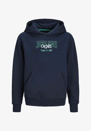 Granatowa bluza z kapturem z przednią kieszenią i białym nadrukiem, zestawiona z jasnoniebieskimi przetartymi dżinsami i białymi trampkami. Gładka tkanina, casualowy fason.