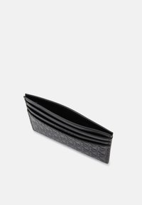 Porta tarjetas de cuero negro acolchado con múltiples ranuras para tarjetas, parte superior abierta y textura suave. Diseño clásico con un aspecto refinado.
