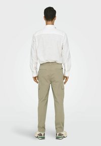 Beegid cargo püksid küljetaskutega, elastse vöökoha ja mugava lõikega, koos valge pikakä sleeveshirtiga.