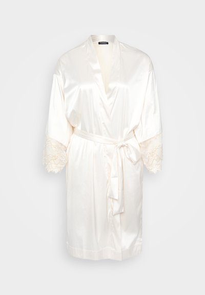 Accappatoio in seta color avorio con maniche ampie, rifiniture in pizzo sui polsini e una cintura da annodare in vita. Texture liscia con un design fluido.