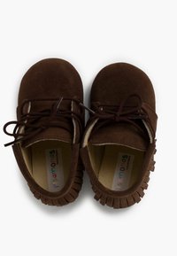 Zapatos de ante marrón con puntera redondeada, cordones en la parte frontal y acentos con flecos a lo largo de la suela. El forro interior y la plantilla son de color beige.