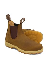 Botas de cuero marrón hasta el tobillo con puntera redonda, paneles laterales elásticos y suela de goma amarilla; cuentan con lengüetas en la parte superior para facilitar su uso.