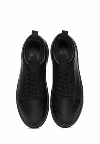 Sneaker in pelle nera con lacci piatti, punta rotonda, linguette sulla collana e una texture liscia. La suola ha un design arrotondato.
