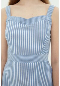 Gestreiftes blau-weißes Kleid mit herzförmigem Ausschnitt, breiten Trägern und einer taillierten Taille, die mit einem horizontal gestreiften Band versehen ist.