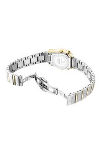 Sidabrinė ir auksinė dviejų tonų metalinė laikrodžio su stačiakampiu korpusu, išskirtiniu ciferblatu ir reguliuojama grandinėlė. Yra sagties uždarymas.