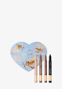 NABLA Cupid's Arrow vakantieset in een hartvormige doos. Bevat vier make-uppotloden in tinten beige, bruin en zwart. De doos heeft een afbeelding van een blauwe lucht met cherubijntjes.