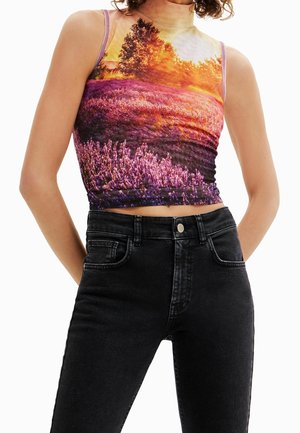 Sleeveless crop top with a vibrant sunset and purple lavender field print worn with high-waisted black jeans.