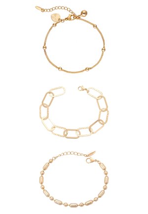 Trzy złote bransoletki: koralikowy łańcuch z małymi okrągłymi zawieszkami, duży prostokątny łańcuch ogniw oraz teksturowana bransoletka z owalnymi i okrągłymi koralikami.