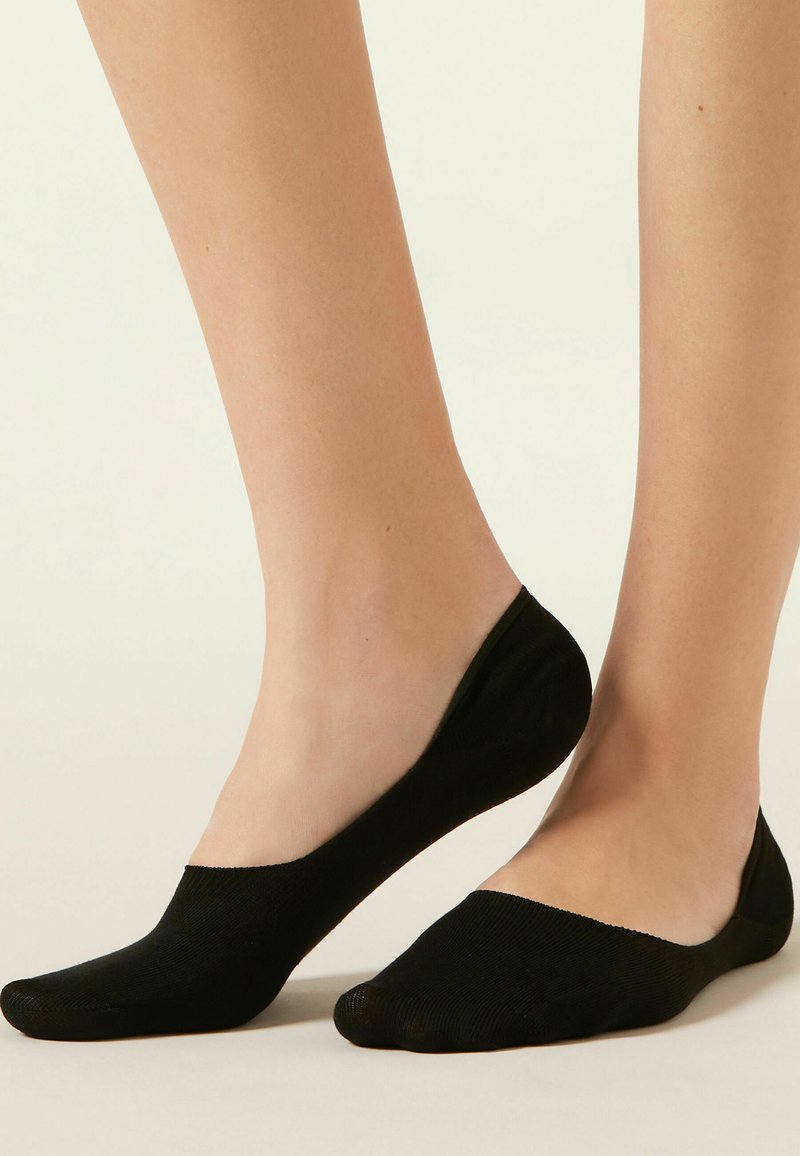 Calcetines negros invisibles con un diseño de corte bajo, que presentan una textura suave y una cinta elástica para un ajuste ceñido, ideales para llevar discretamente.
