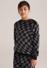 Sudadera de forro polar a cuadros en negro y gris con una textura suave y cuello acanalado, que presenta mangas largas y un detalle de marca visible en el puño.