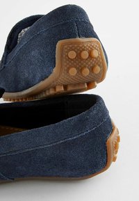 Mocassini in suede blu navy con una superficie testurizzata. Suola in gomma con dettagli a grip circolari per trazione e durata.