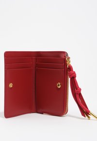 Czerwona skórzana portmonetka z złotymi akcentami, posiadająca zamek błyskawiczny, kieszonki na karty oraz pleciony detal paska z boku. Wnętrze ma gładką teksturę.
