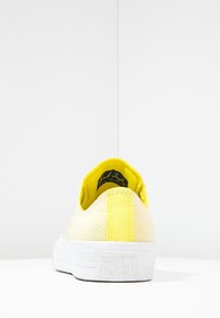 Baskets basses jaunes avec une tige texturée, un contrefort jaune contrastant et une semelle en caoutchouc blanche avec une marque en relief.