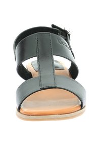 Sandale en cuir noir avec une semelle plate, dotée de deux larges sangles et d'une boucle réglable. Accent marron sur le rembourrage pour un contraste.