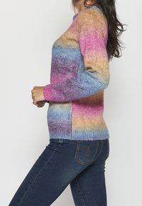 Maglione lavorato a maglia con righe a gradiente in rosa, viola e blu. Collo rotondo, maniche lunghe e orlo a coste con una consistenza morbida.