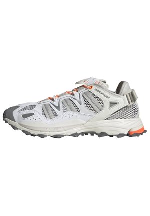 Weiße und graue Sportschuhe mit Mesh-Einsätzen, orangefarbenen Schnürsenkeln, robustem Sohlenprofil und "HYPERGLIDE"-Markierung an der Seite.