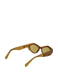 Óculos de sol translúcidos castanhos com uma moldura angular distinta, lentes verde-amarelas e um detalhe de logotipo nas hastes.